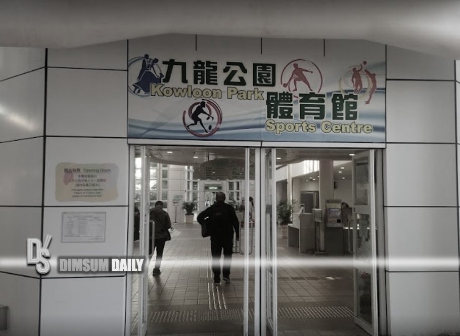 A group of people is walking into the Kowloon Park Sports Centre, which features a signboard with the name and sports icons above the entrance.
