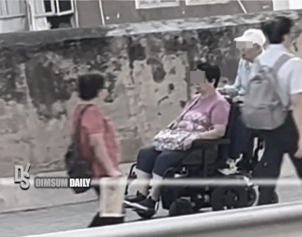 Elderly couple on dual electric wheelchair at speed on pedestrian slope